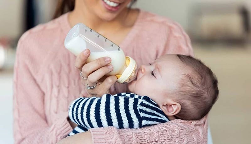 Quantas Mamadeiras o Bebê Deve Tomar por Dia? 1 mae alimentando seu filho bebe com mamadeira
